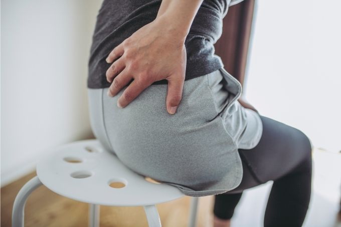 What causes lower back pain just above the buttocks?